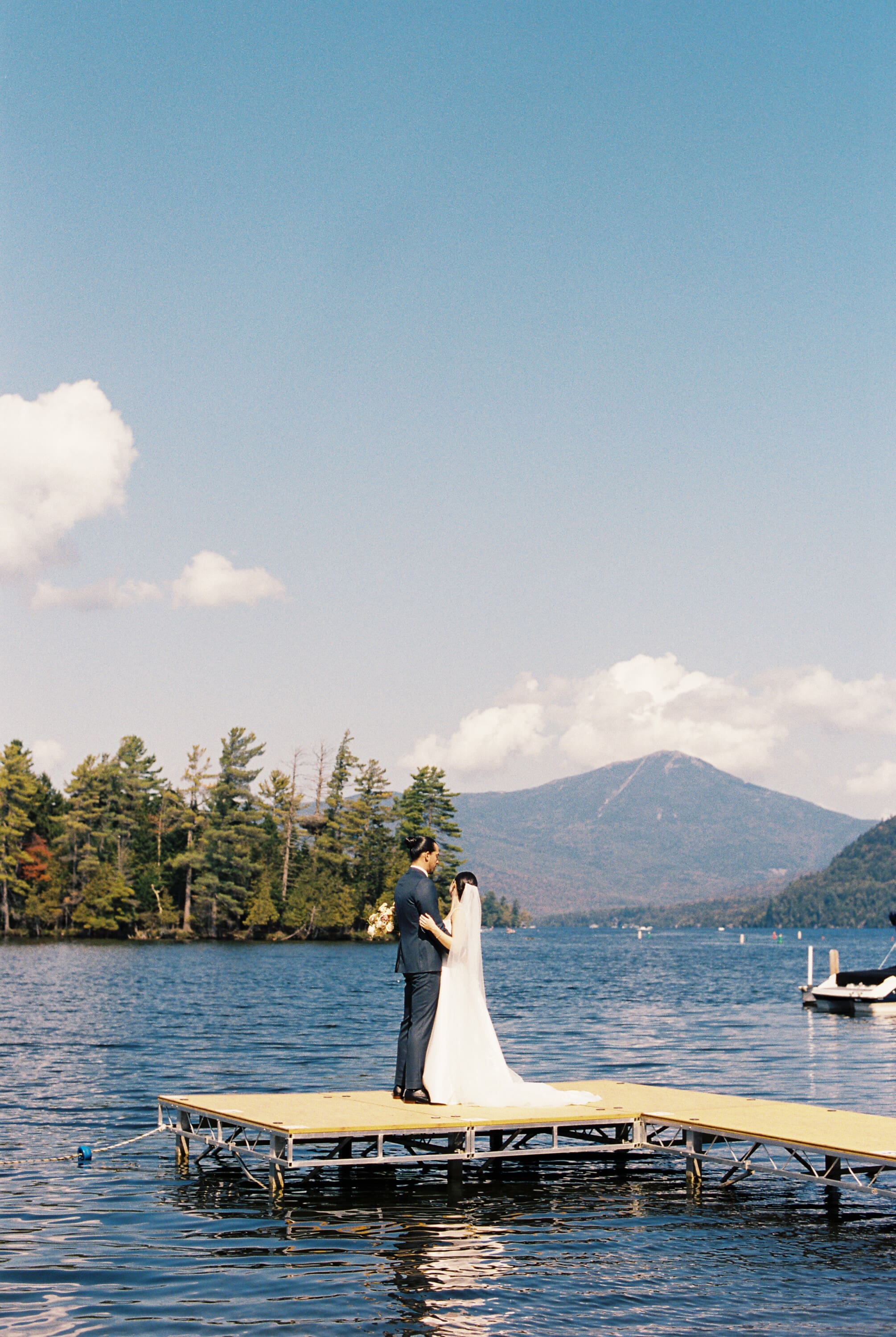 couple photographed lookinf out over lake placid at the Canoe Club which is the lakefront at the whiteface lodge in lake placid